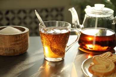 Tasty tea and sugar on dark table, closeup