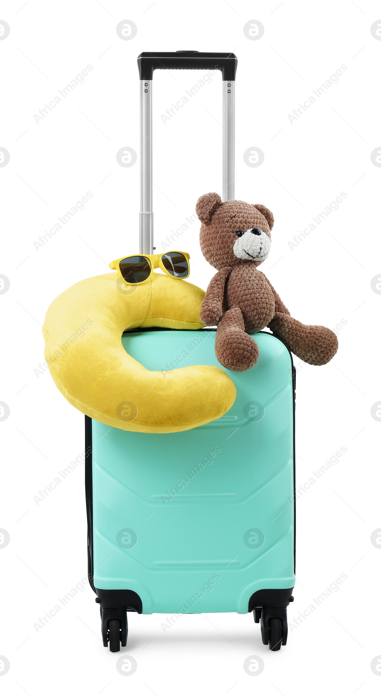 Photo of Soft travel pillow and toy bear on turquoise suitcase isolated on white