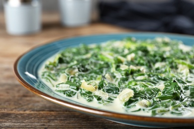 Tasty spinach dip on wooden table, closeup