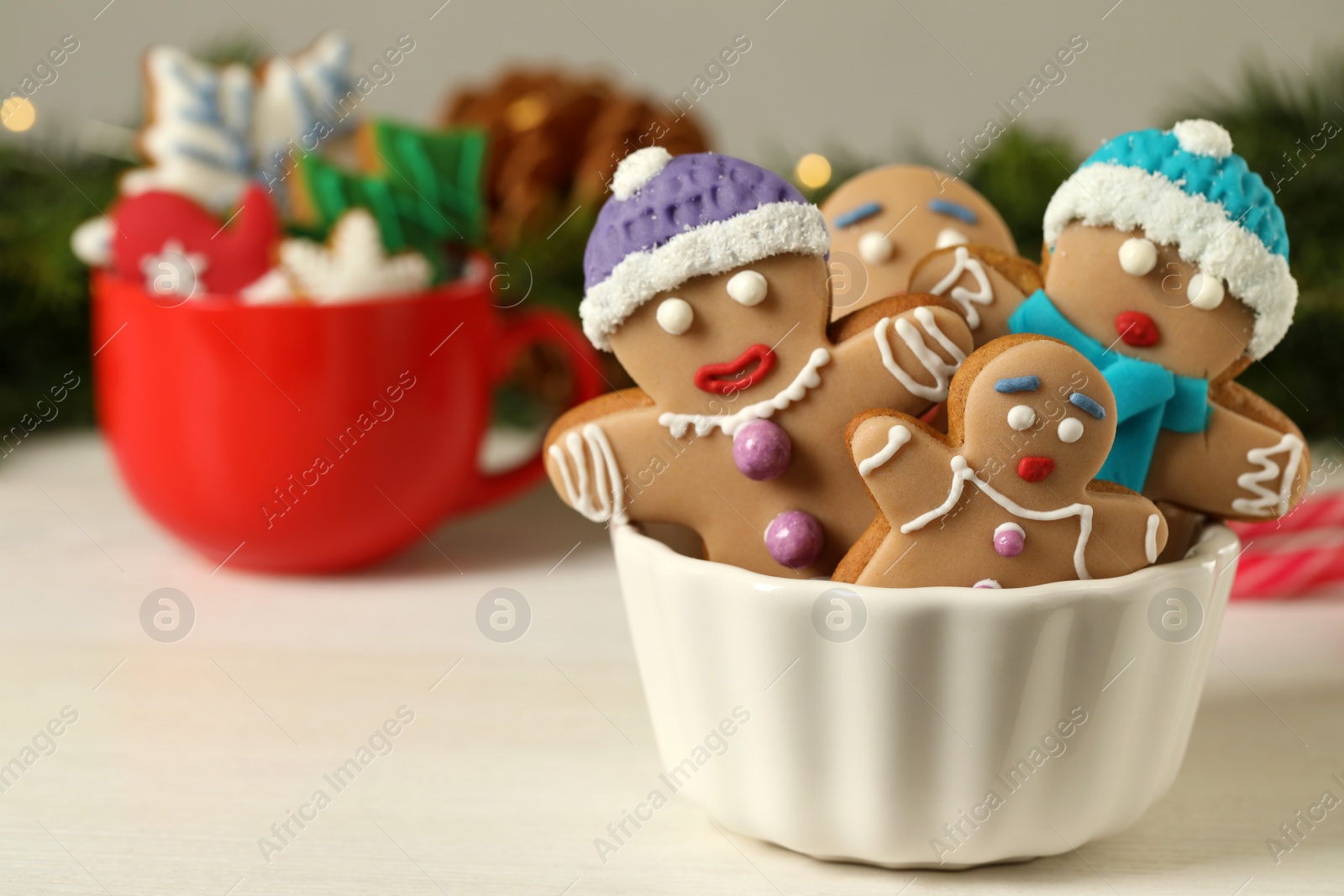 Photo of Delicious homemade Christmas cookies in bowl on white wooden table against blurred festive lights. Space for text