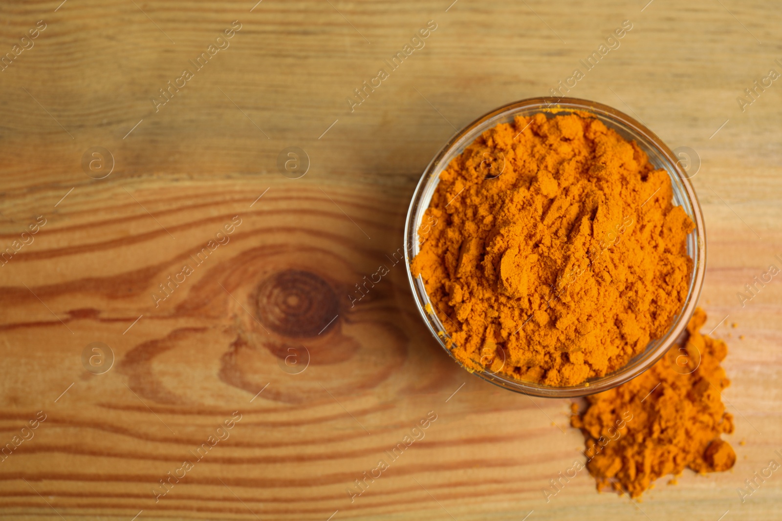 Photo of Bowl with saffron powder on wooden table, top view. Space for text