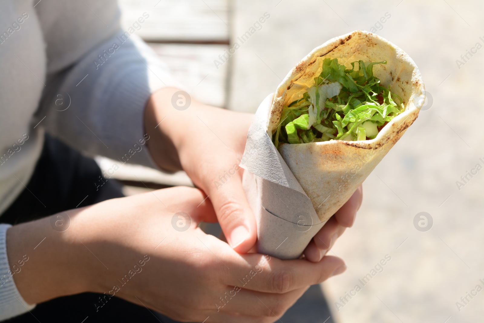 Photo of Woman holding delicious vegetable roll outdoors, closeup