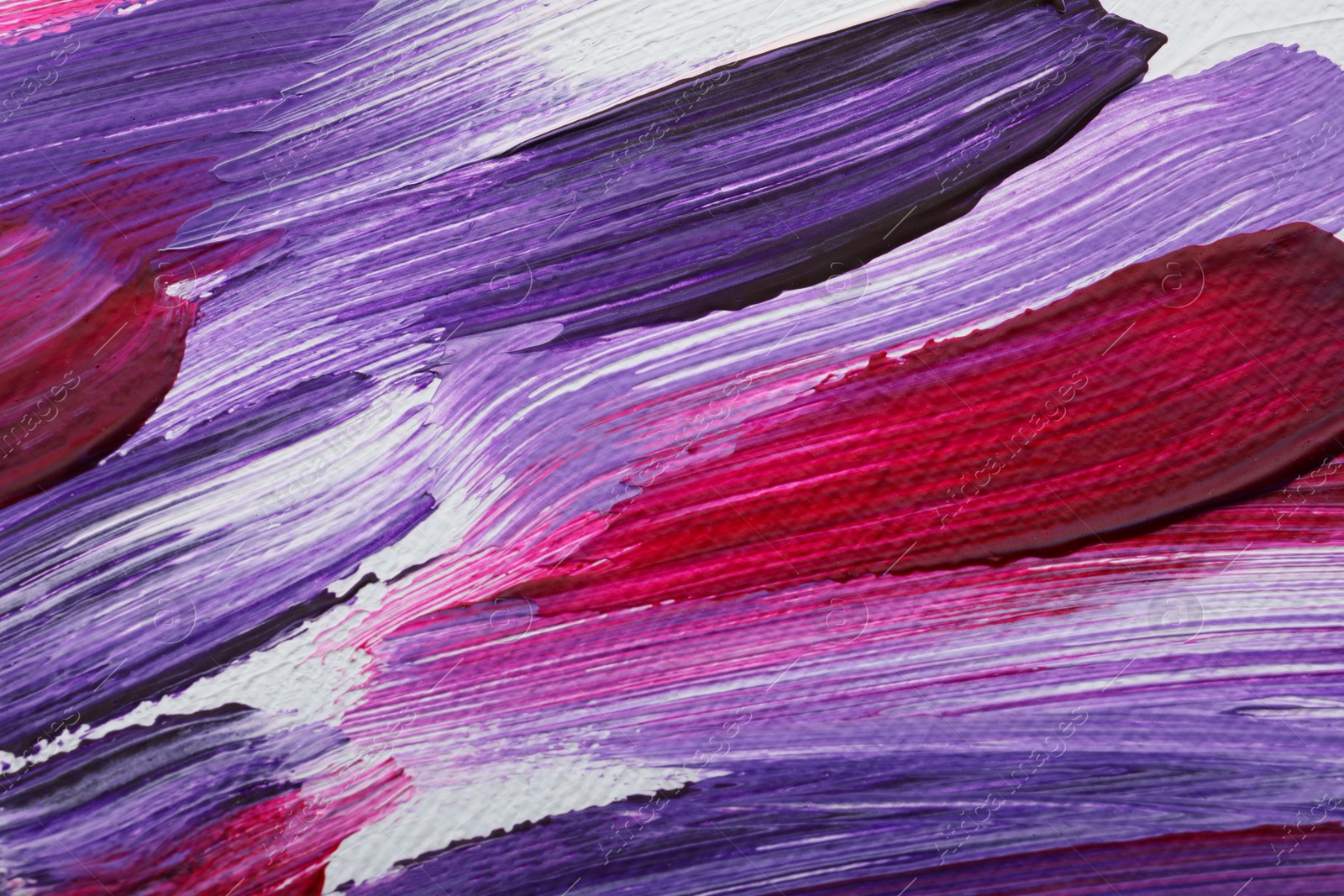 Photo of Strokes of colorful oil paints on white canvas, closeup