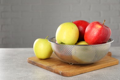 Photo of Fresh ripe apples in colander on light grey table. Space for text