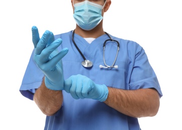 Doctor in protective mask putting on medical gloves against white background, closeup