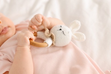 Photo of Cute little baby with toy on white sheets, closeup
