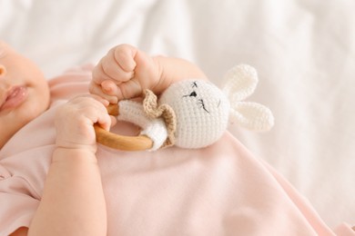 Cute little baby with toy on white sheets, closeup