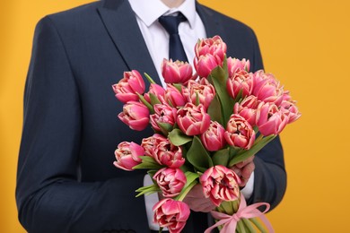 Photo of Man with beautiful bouquet on orange background, closeup