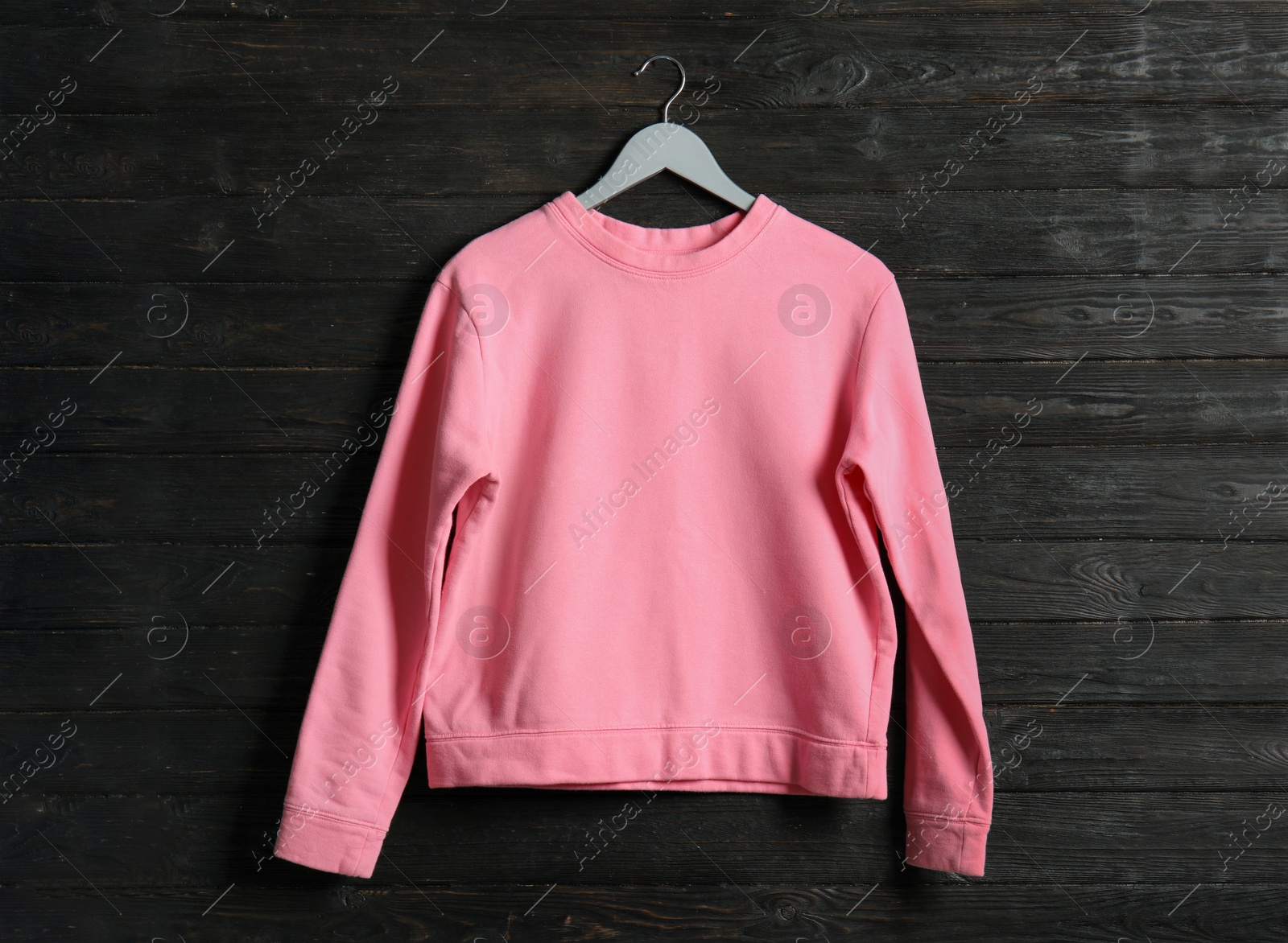 Photo of Hanger with pink sweatshirt on wooden background. Mockup for design