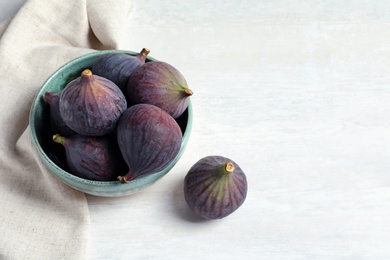 Bowl with fresh ripe figs on light background. Space for text