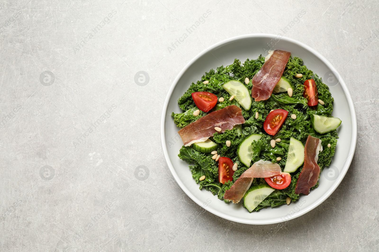 Photo of Delicious salad with kale leaves on grey table, top view. Space for text