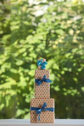 Photo of Stack of beautifully wrapped gift boxes on white table  near window