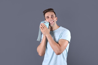 Young man holding toilet paper roll on color background