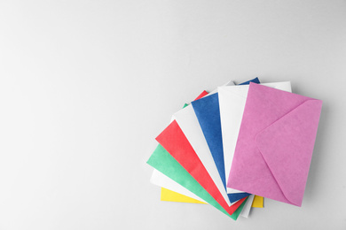 Photo of Colorful paper envelopes on light background, top view. Space for text