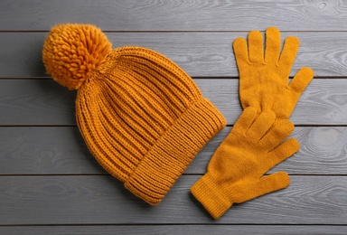 Photo of Stylish gloves and hat on grey wooden background, flat lay