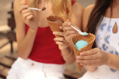 Photo of Young women with ice cream spending time together outdoors, closeup