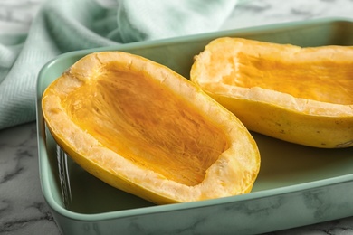 Photo of Baking dish with cut spaghetti squash on table