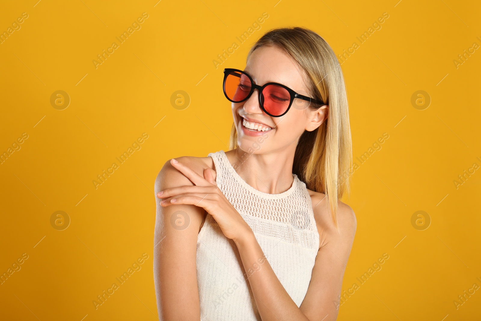Photo of Beautiful woman in stylish sunglasses on yellow background