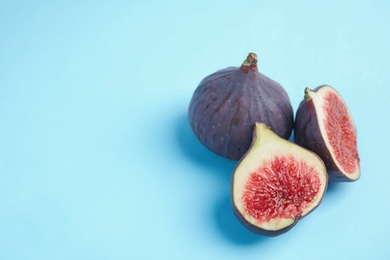 Delicious ripe figs on light blue background, closeup. Space for text