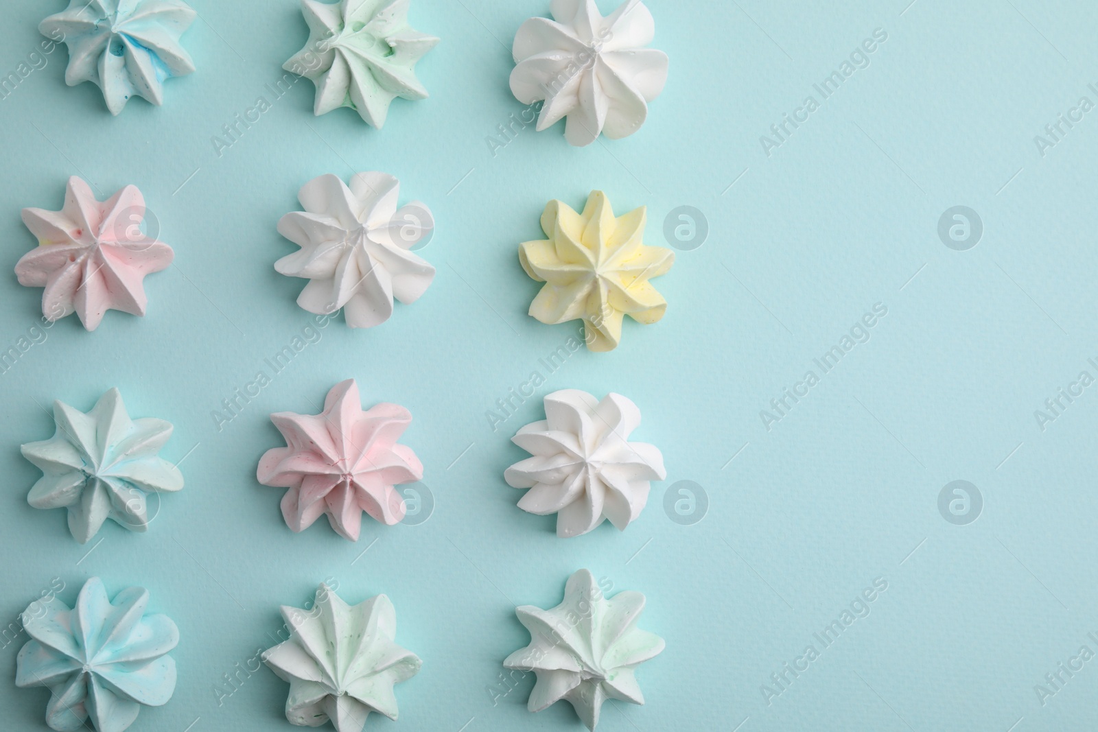 Photo of Delicious meringue cookies on light blue background, flat lay. Space for text