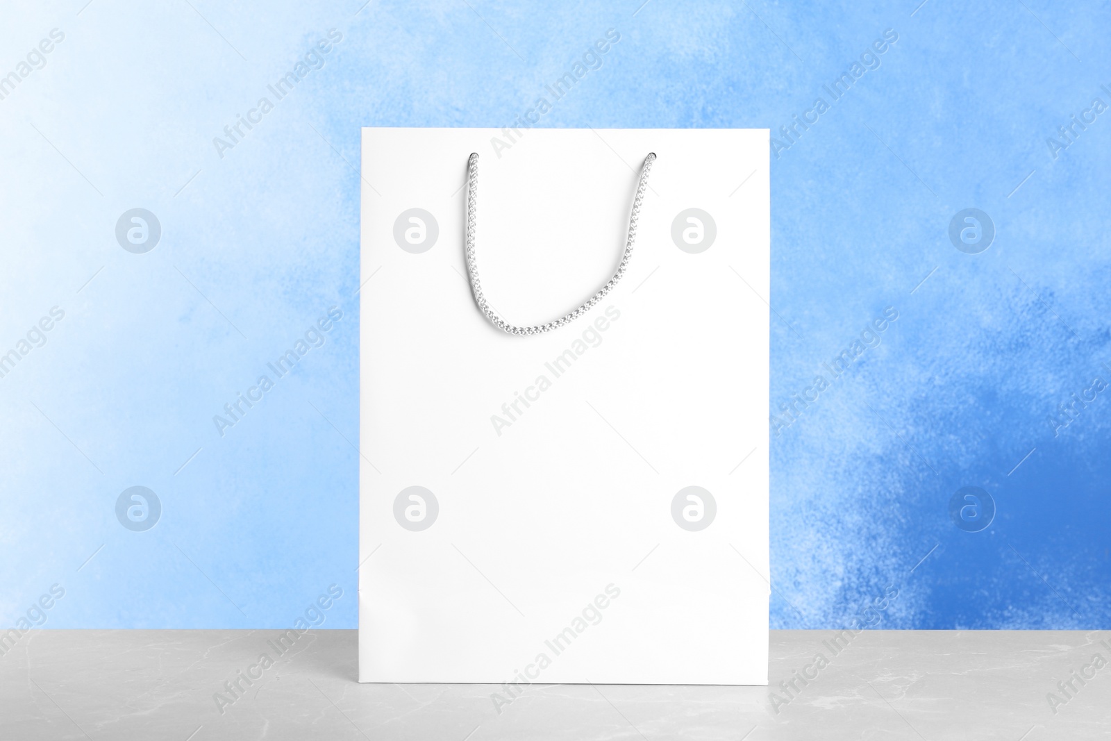 Photo of Mockup of paper shopping bag on table against color background