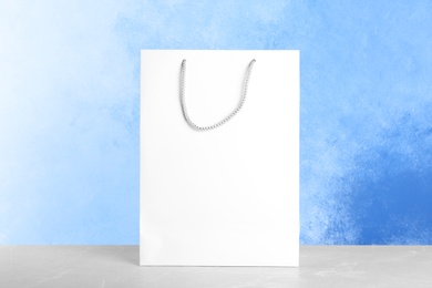 Photo of Mockup of paper shopping bag on table against color background