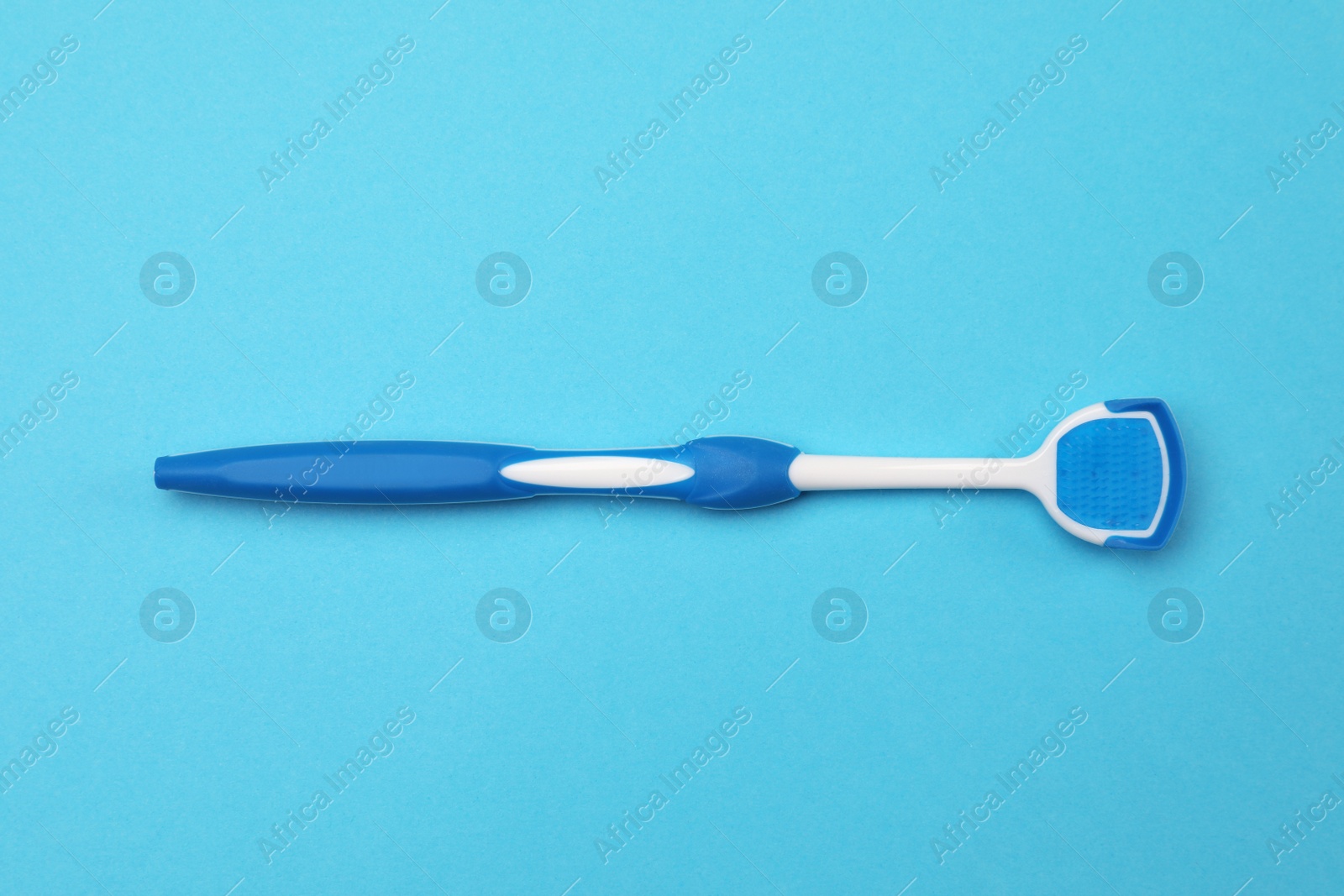 Photo of Tongue cleaner on light blue background, top view