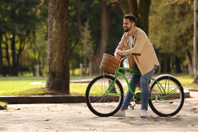 Young man with bicycle in park, space for text