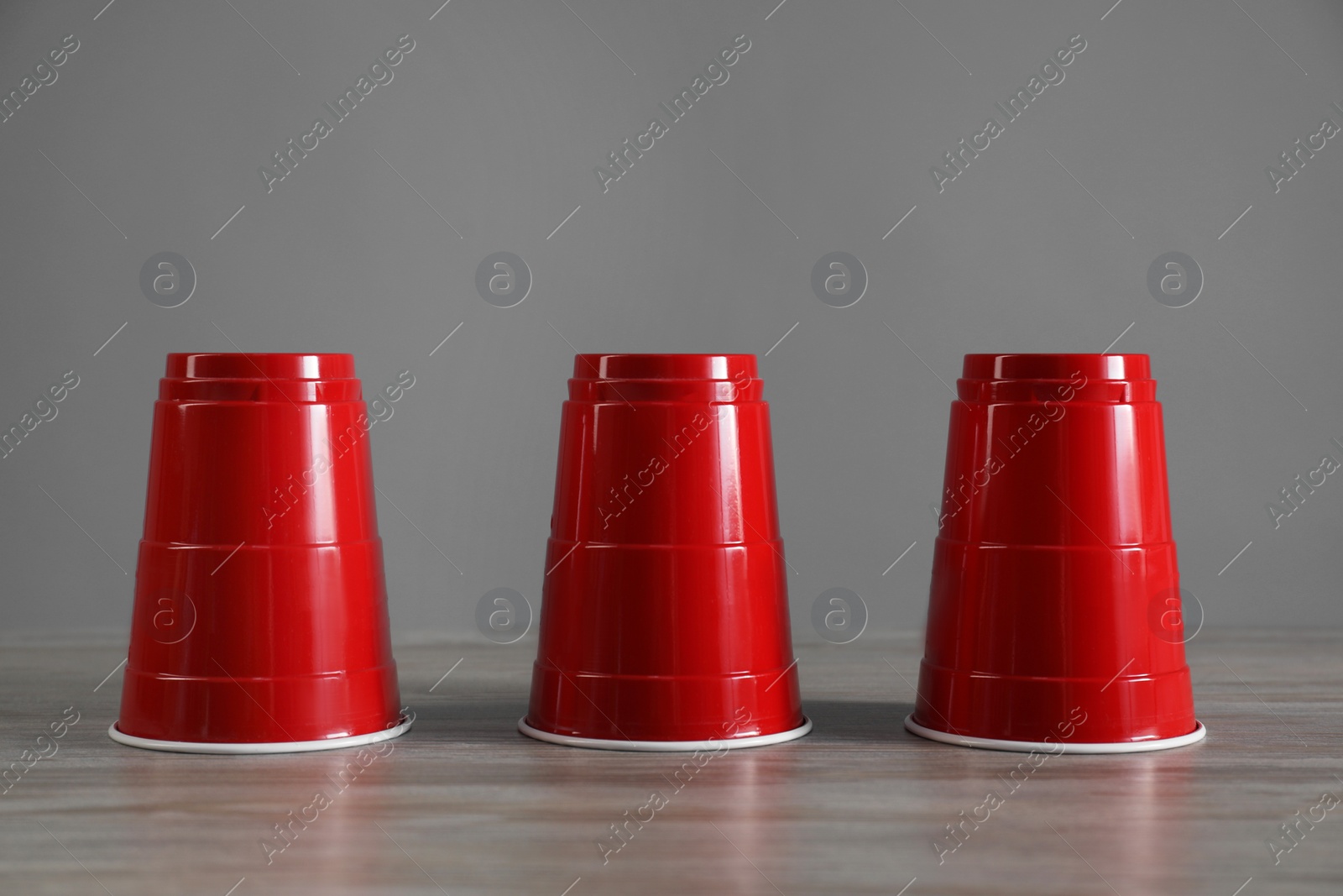 Photo of Shell game. Three red cups on wooden table