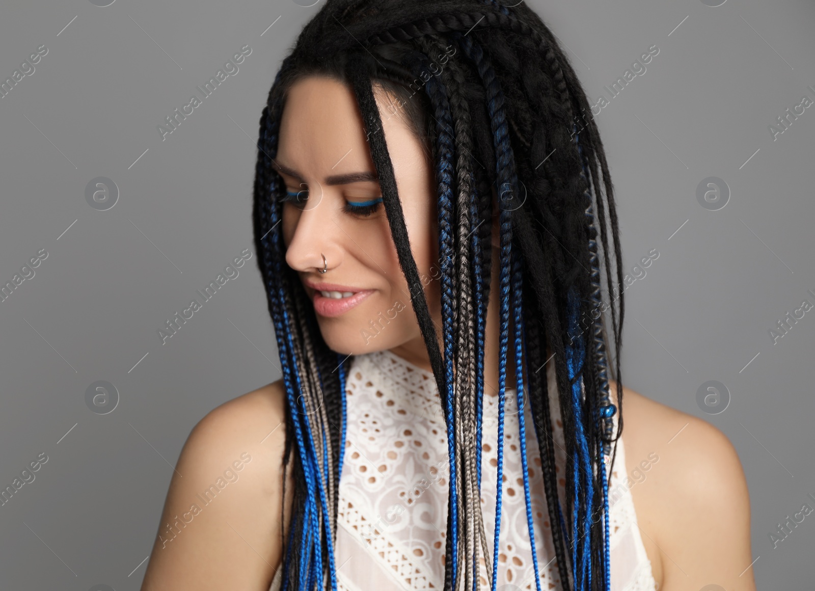 Photo of Beautiful young woman with nose piercing and dreadlocks on grey background