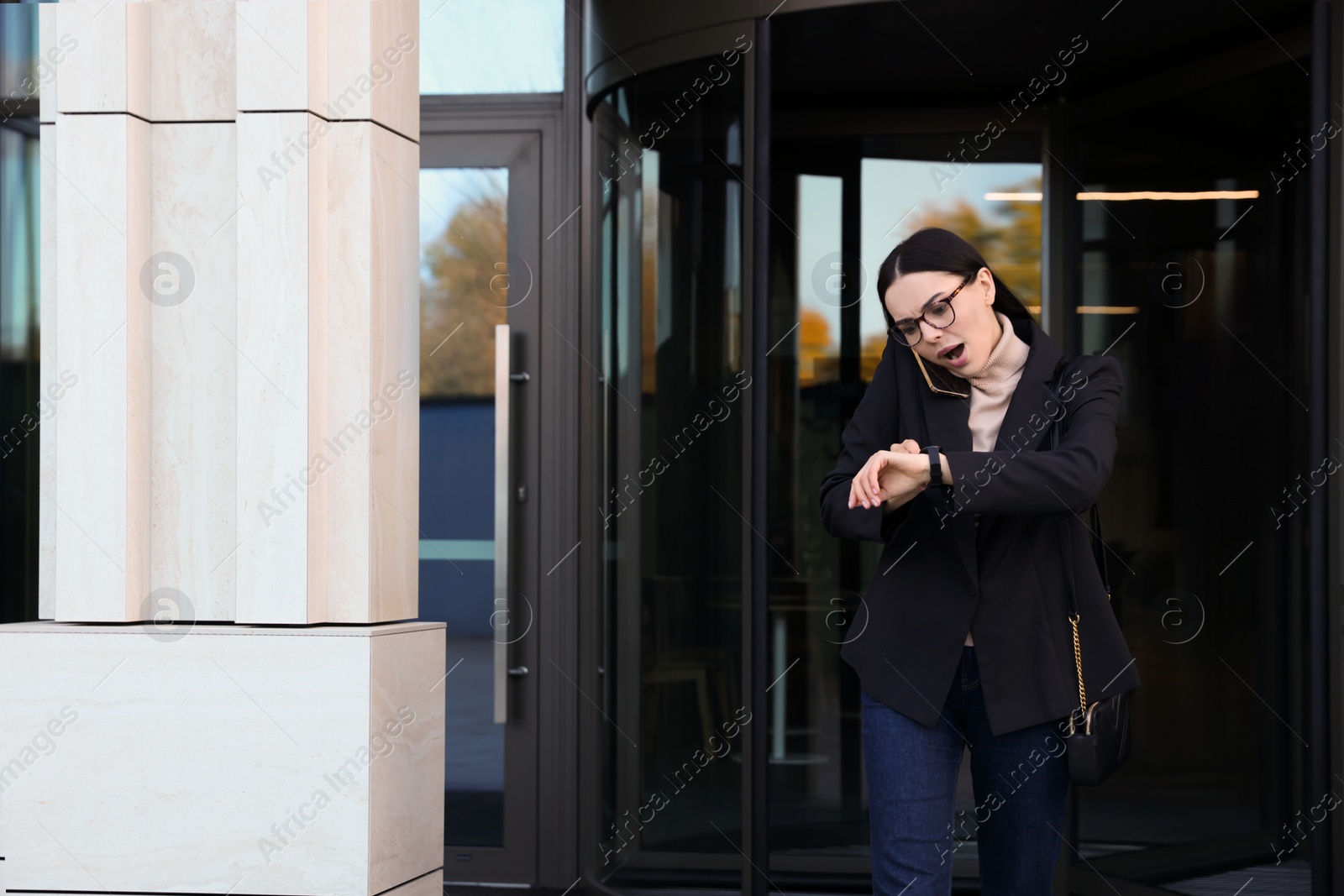 Photo of Emotional woman checking time while talking on smartphone outdoors. Being late concept