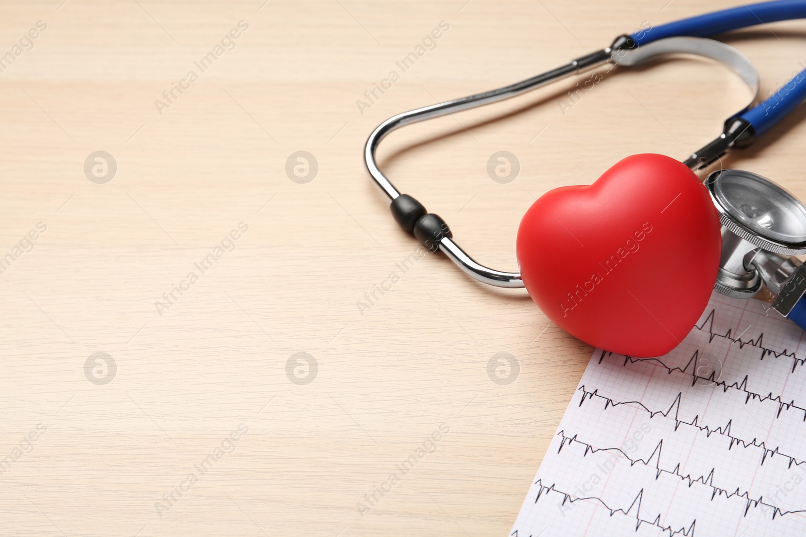 Photo of Stethoscope, cardiogram, red decorative heart and space for text on wooden background. Cardiology concept
