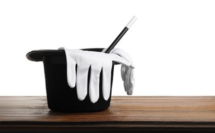 Photo of Magician's hat, gloves and wand on wooden table against white background