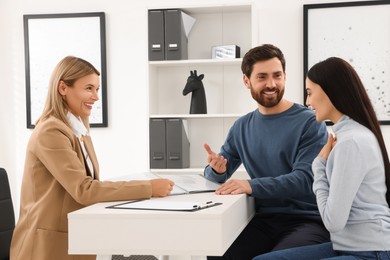 Photo of Real estate agent working with couple in office