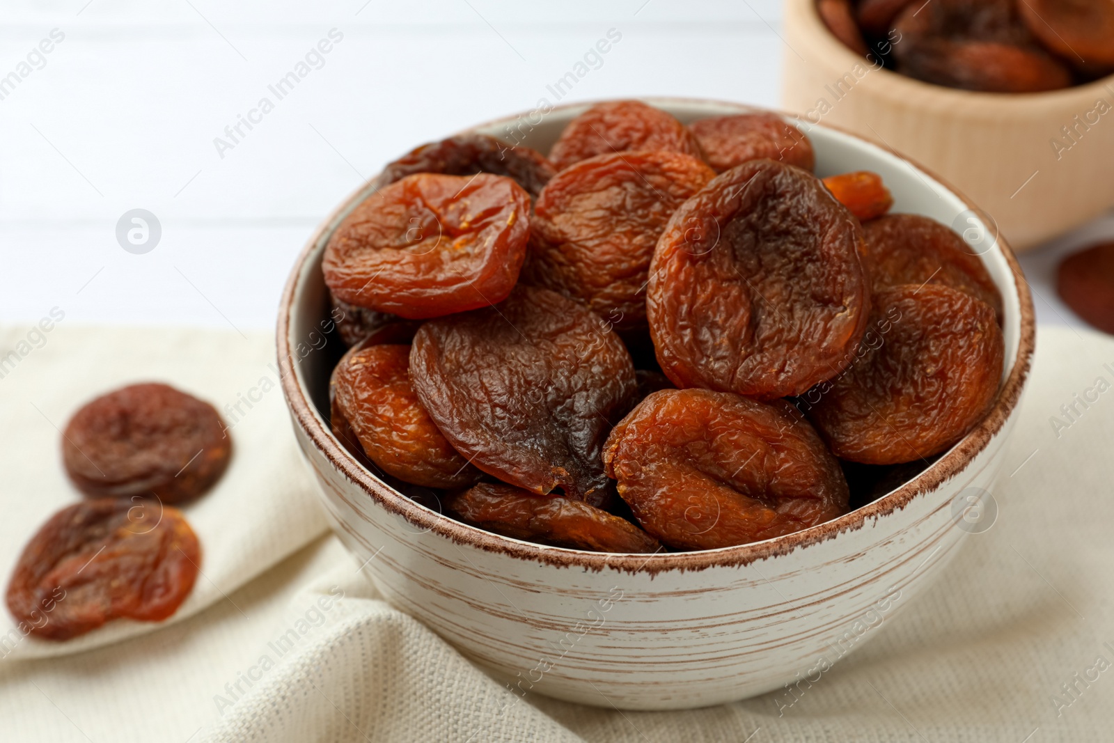Photo of Bowl of tasty apricots on table, closeup. Dried fruits