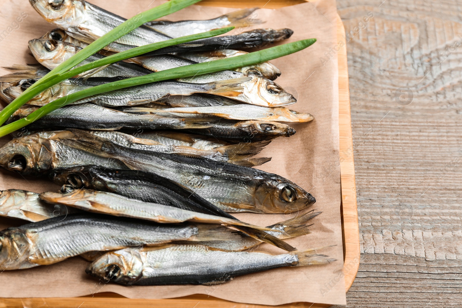 Photo of Tasty dried fish with fresh onion on wooden table, above view