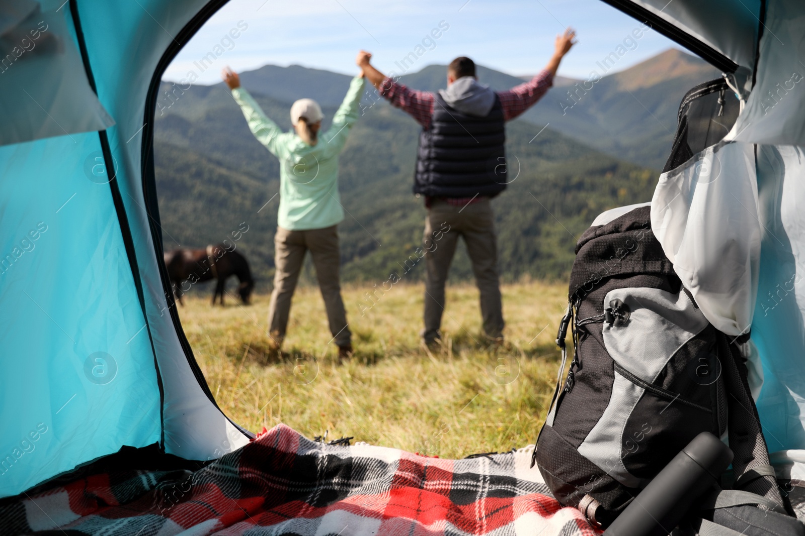 Photo of Couple in mountains on sunny day, view from camping tent