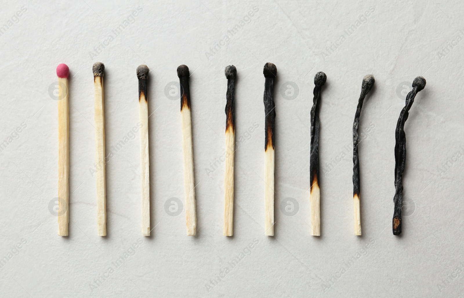 Photo of Row of burnt matches and whole one on light background, flat lay. Human life phases concept