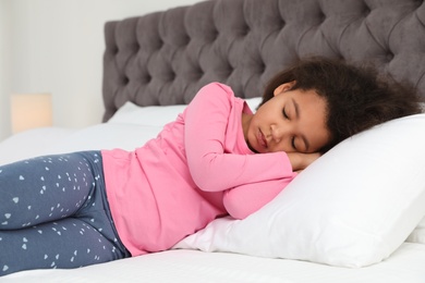 Photo of Cute little African-American girl sleeping in bed