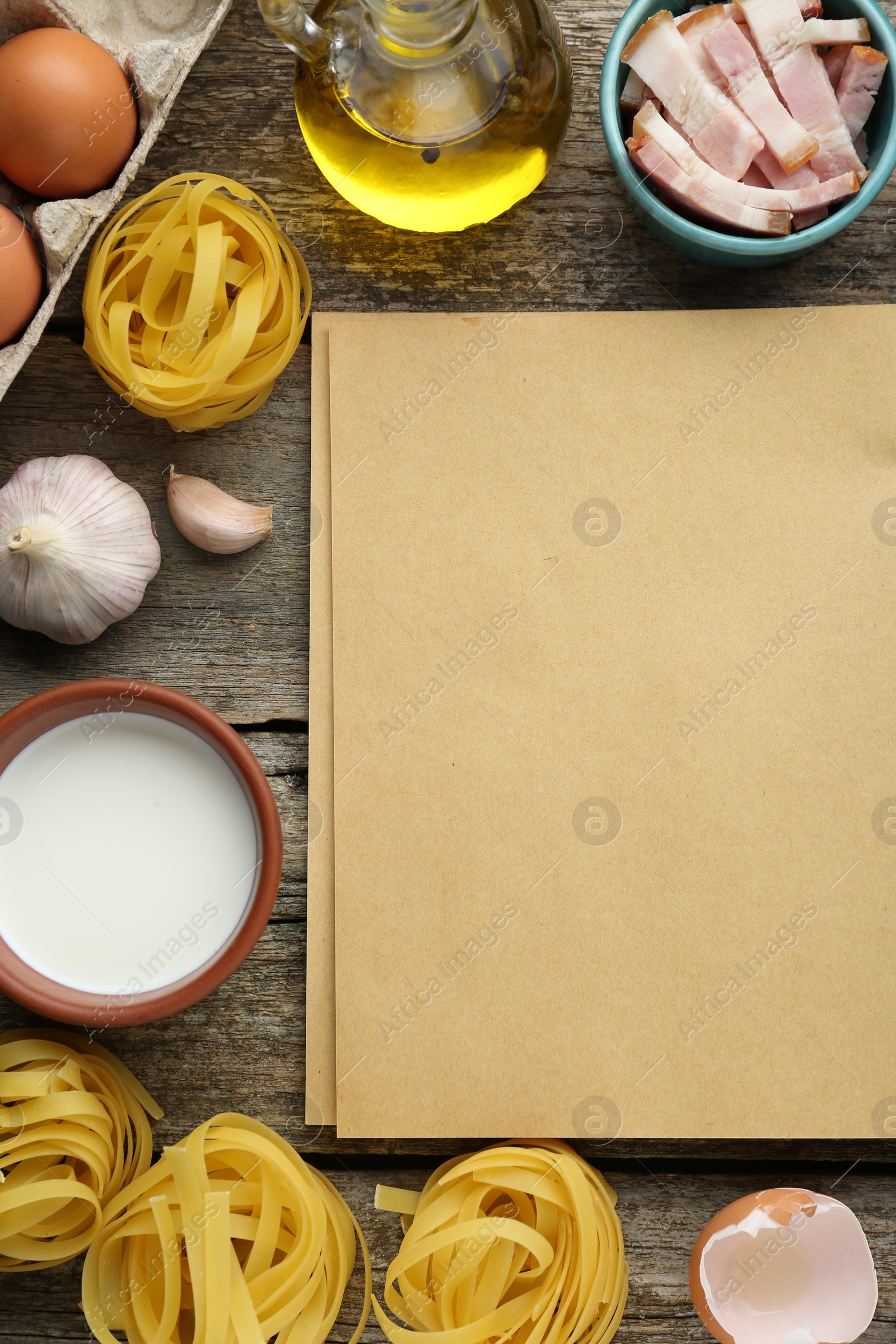 Photo of Blank recipe book and different ingredients on wooden table, flat lay. Space for text