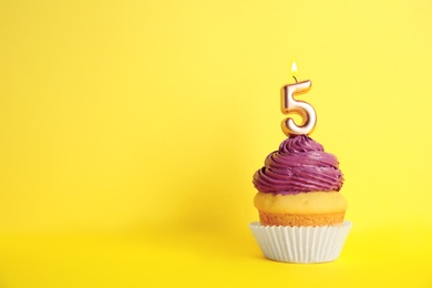 Photo of Birthday cupcake with number five candle on yellow background, space for text