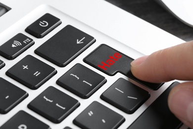 Image of Woman pressing button with text Hate on computer keyboard, closeup