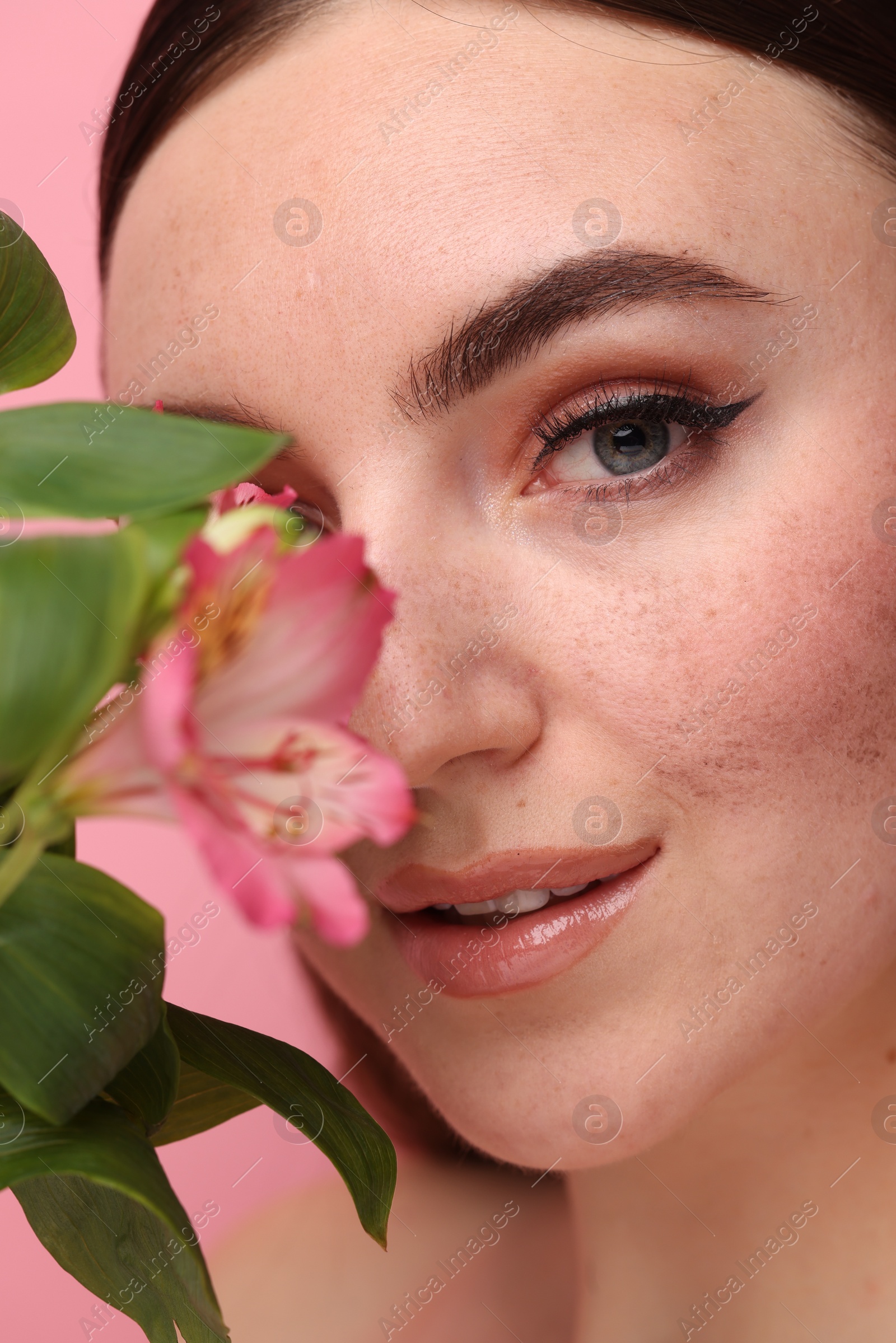 Photo of Beautiful woman with fake freckles and flower, closeup