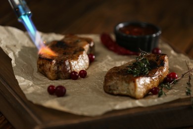 Photo of Cooking meat medallions with manual gas burner on wooden table in photo studio, closeup. Food stylist