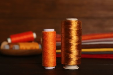 Photo of Different color sewing threads on black wooden table