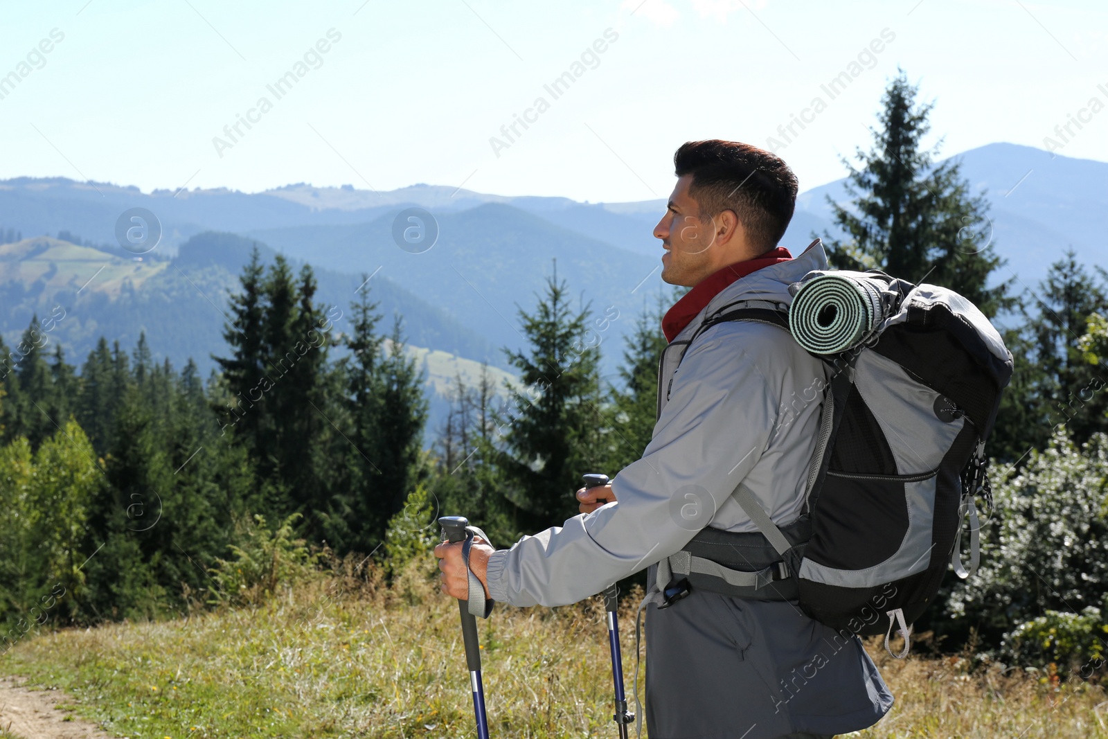 Photo of Tourist with backpack and trekking poles enjoying mountain landscape