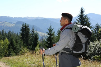 Photo of Tourist with backpack and trekking poles enjoying mountain landscape