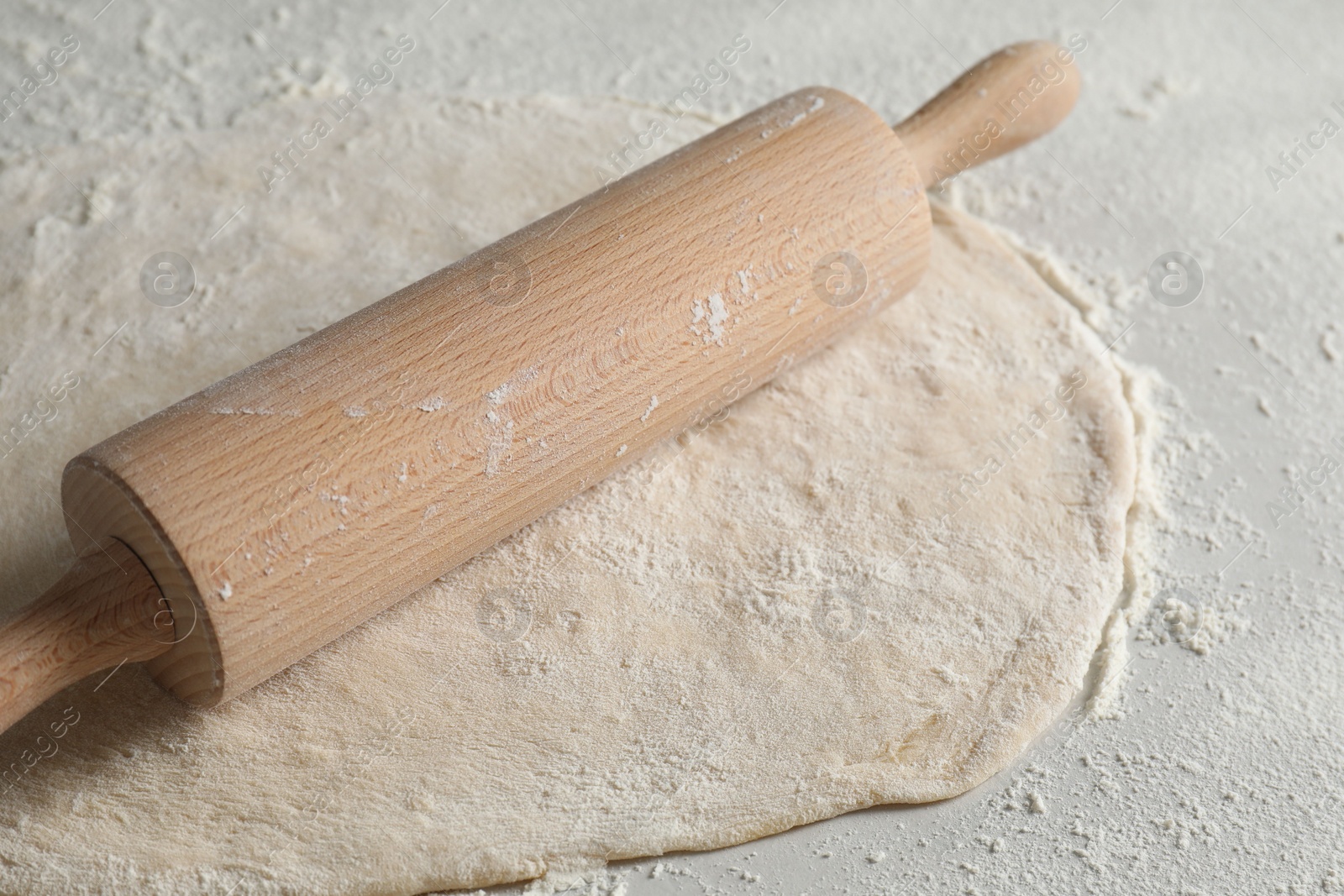 Photo of Raw dough and rolling pin on table