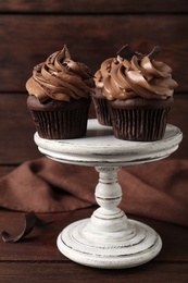 Delicious cupcakes decorated with cream on wooden table