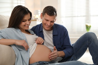 Photo of Young pregnant woman with her husband at home